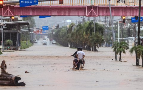 Dos personas en una moto transitan por una calle inundada en Acapulco (México).