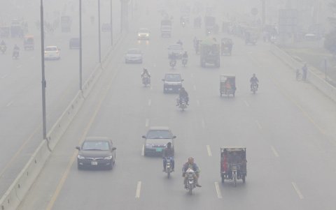 Personas viajan en coches y motocicletas bajo la nube de contaminación en Lahore (Pakistán).