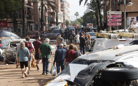 Varias personas caminan entre los vehículos destrozados en Paiporta, Valencia.