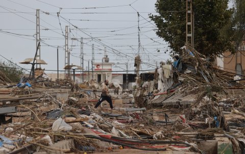 Un hombre cruza las destrozadas vías de la línea 1 del metro de Valencia en Paiporta. Las calles son auténticos barrizales.