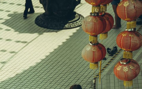 Una mujer asiática espera con un ramos de flores a la entrada de un lugar donde habrá una ceremonia de matrimonio.