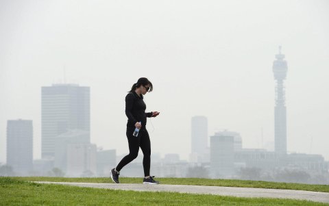 Una mujer camina en una zona de Londres, mientras se observa una capa de humo.