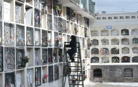 Una mujer observa la tumba de su familiar en el sur de Quito, en medio de otras que están adornadas con flores.
