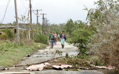 Unas personas caminan por una calle afectada tras el paso del huracán Rafael, este jueves en Playa Majana, en la provincia de Artemisa (Cuba).