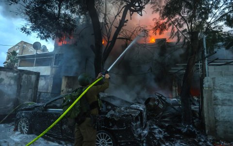 Un soldado israelí trabaja para extinguir un incendio después de que cohetes disparados desde Líbano impactaran en la ciudad de Kiryat Ata, en el distrito de Haifa