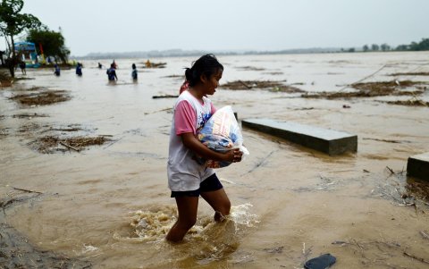 Una aldeana lleva sus pertenencias a lugares más seguros mientras evacua sus hogares a lo largo de un río crecido causado por las fuertes lluvias del tifón.