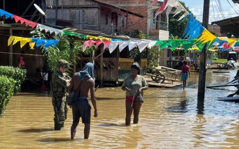 Un soldado con dos personas en una calle inundada, este lunes en Alto Baudó (Colombia).