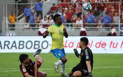Rafael Romo (d) de Venezuela disputa el balón con Vinícius Jr. de Brasil, durante un partido de las eliminatorias sudamericanas al Mundial de Fútbol 2026, en el estadio Monumental, en Maturín