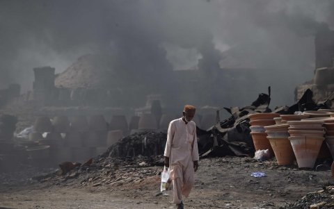 Un hombre camina mientras al fondo sale humo de una fábrica de cerámica en Pakistán, el 10 de noviembre de 2024.