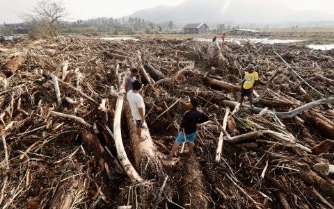 Aldeanos filipinos se paran sobre troncos y escombros arrastrados por el tifón Usagi en el municipio costero de Santa Ana, provincia de Cagayán, Filipinas, el 15 de noviembre de 2024.