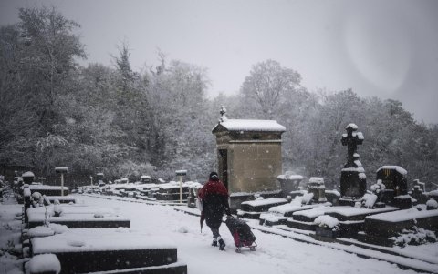 Una mujer camina por un sendero cubierto de nieve en un cementerio durante una nevada en Romainvile, cerca de París, Francia, el 21 de noviembre de 2024.