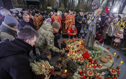 Ucranianos colocan velas en el monumento conmemorativo 'Amarga Memoria de la Infancia' con la estatua 'Niña con Orejas de Grano'.