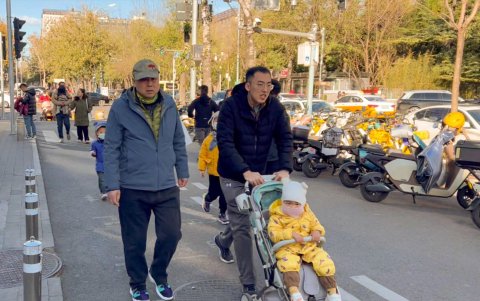 Dos personas llevan a un chino en una de las calles de Pekín.