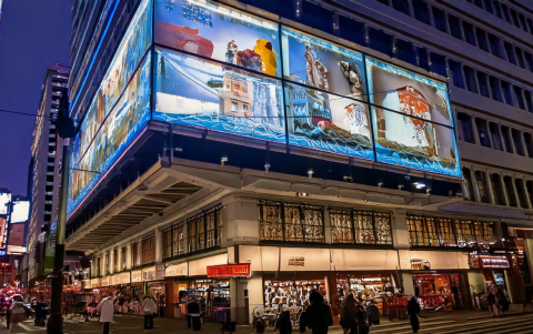 Un enorme mural digital domina la escena, destacando símbolos culturales locales.