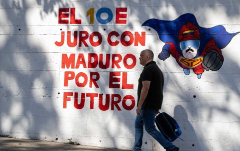 Un hombre camina frente a un mural con el mensaje 