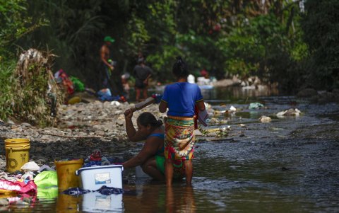 Dos mujeres que lavan ropa en un río contaminado con basura en la frontera entre Panamá y Colombia.