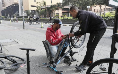 Un mecánico arregla una bicicleta en la ciclovía domingo, en Bogotá