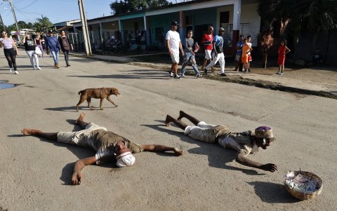Leandro, cubano de 20 años, se arrastra junto con su hermano bajo los tempestuosos rayos del sol de mediodía en las afueras de La Habana.