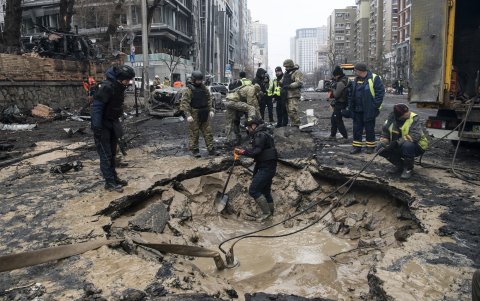Los trabajadores drenan el agua de un agujero de bombardeo mientras expertos y oficiales de policía trabajan en el lugar de un ataque con misiles en el centro de Kiev, el 20 de diciembre de 2024.