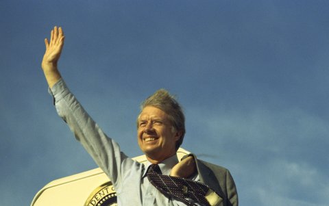Jimmy Carter saludando en lo alto de las escaleras del Air Force One antes de partir hacia Los Ángeles para hablar en la convención del United Auto Workers, el 17 de mayo de 1977.