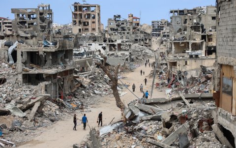 Los palestinos caminan por un camino de tierra bordeado de escombros de edificios destruidos en el barrio de Shujaiya de la ciudad de Gaza el 7 de octubre de 2024