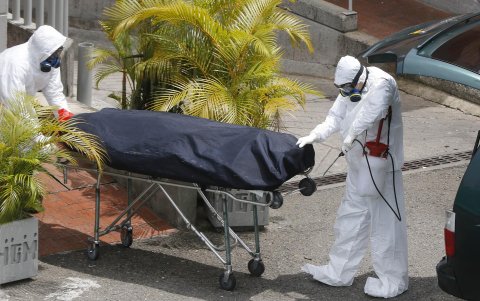 Personal funerario lleva el cuerpo de una víctima covid-19 rumbo a un vehículo hoy, en el Hospital General de Medellín (Colombia).