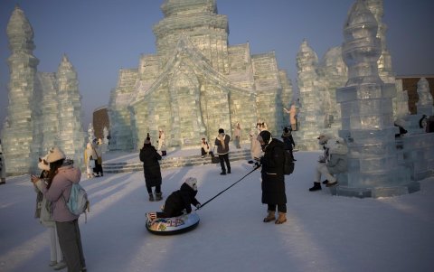 Los visitantes se encuentran junto a uno de los edificios de hielo en el Festival de Hielo y Nieve de Harbin en Harbin, provincia de Heilongjiang, China,