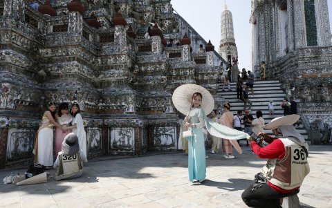 Varios turistas extranjeros vestidos con trajes tradicionales tailandeses posan para fotografías conmemorativas en el Templo del Amanecer.