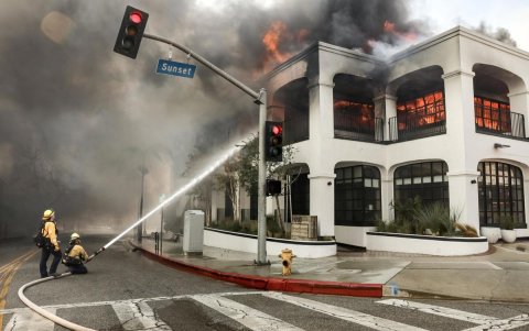 Los bomberos luchan contra las llamas que envuelven un edificio durante el incendio forestal de Palisades en el barrio de Pacific Palisades de Los Ángeles, California.