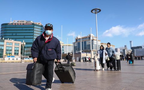 La gente camina con sus pertenencias en la estación de tren de Beijing en Pekín,