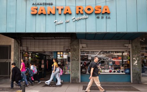 Varias personas caminan frente a las vitrinas de un local comercial este martes, en Caracas (Venezuela).