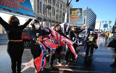 Manifestantes del grupo activista Revcom Corps para la Emancipación de la Humanidad destruyen banderas estadounidenses, MAGA y confederadas en la estrella.