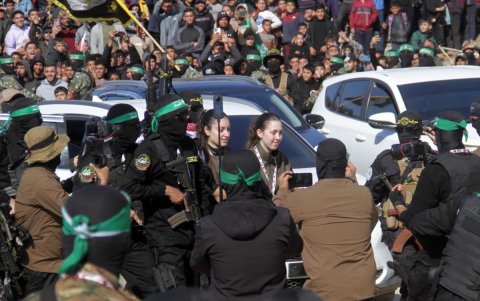 Las rehenes israelíes Naama Levy (c, dcha) y Karina Ariev (c, izq) caminan antes de ser entregados al representante del Comité Internacional de la Cruz Roja (CICR) por militantes de Hamas.