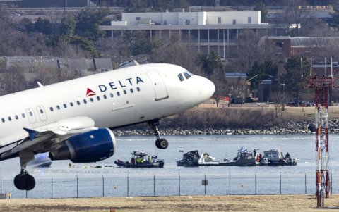 Un vuelo de Delta Airlines despega del aeropuerto Ronald Reagan frente a los restos de un avión comercial que chocó con un helicóptero militar, en Arlington, el 30 de enero de 2025.