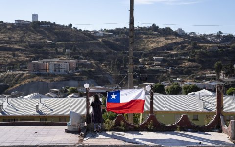 Una mujer sostiene una bandera durante la conmemoración del aniversario del megaincendio este domingo, en Viña del Mar (Chile).
