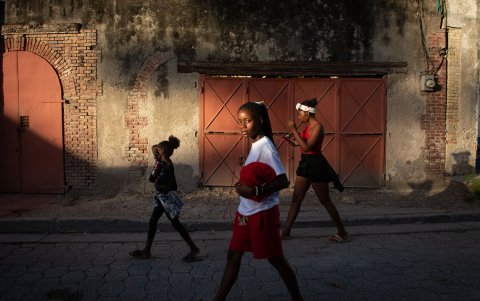 Tres jóvenes caminan de paso por un barrio en busca de un sitio para hacer deporte, mientras a 80 km Haití arde por la violencia.