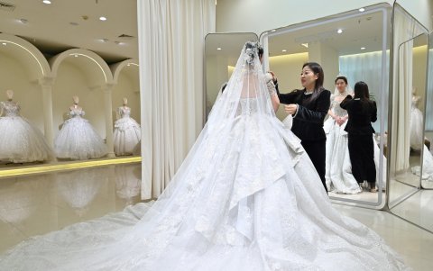 Una mujer se ajusta su vestido de novia en una tienda de novias en Luliang, provincia de Shanxi, en el norte de China, el 11 de febrero de 2025