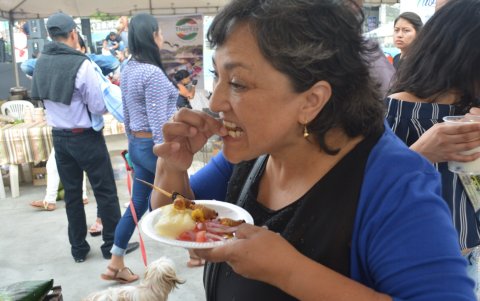 Una señora disfruta de un pincho de chontacuro, un alimento muy sabroso.