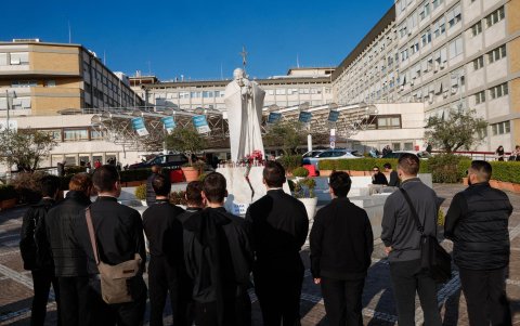 Sacerdotes de Estados Unidos rezan ante una estatua del Papa San Juan Pablo II en el exterior del Hospital Universitario Gemelli, donde el Papa Francisco está hospitalizado.