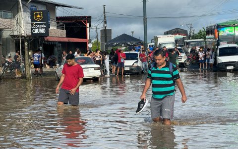 Ciudadanos caminan entre el agua acumulada en una vía en la parroquia Calderón, en Portoviejo, zona rural de Portoviejo.