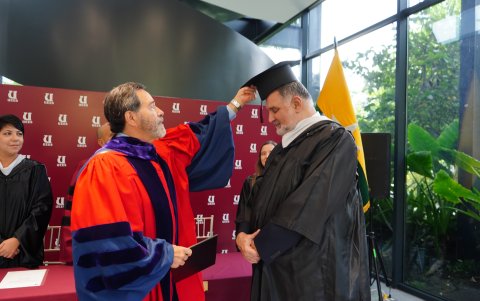 Pedro Pablo Gómez recibe el birrete de manos de Carlos Ortega Maldonado, canciller de la UEES.