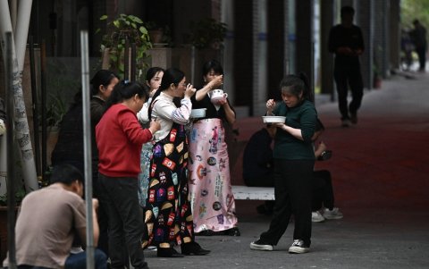 Los empleados de un taller de costura de ropa comiendo durante una pausa para la cena en Guangzhou, provincia de Guangdong, en el sur de China.