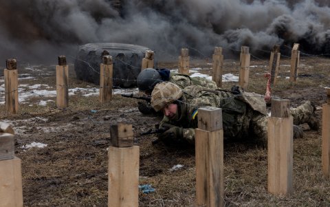 Los militares ucranianos de la 24.ª Brigada Mecanizada se arrastran bajo alambres de púas, mientras participan en un ejercicio de entrenamiento en la región oriental de Ucrania.