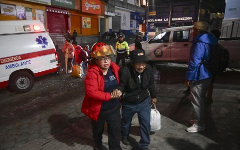 Una persona de la tercera edad es ayudado a movilizarse por miembros de socorro. Los evacuados llegan a un refugio después de huir de su aldea.