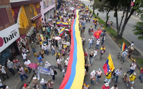 Decenas de personas que participan en una manifestación este martes, en Cali (Colombia), levantan una larga bandera del país.