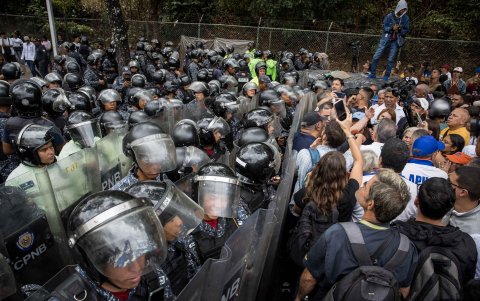 Personas se manifiestan durante una protesta frente a integrantes de la Policía Nacional Bolivariana (PNB) que custodian los accesos a la Universidad Central de Venezuela.