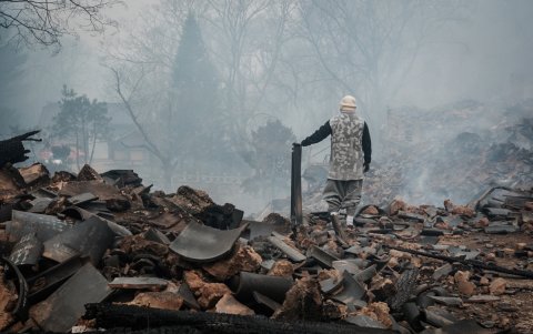 Un auxiliar caminando sobre los escombros causados tras la expansión de los incendios forestales surcoreanos.