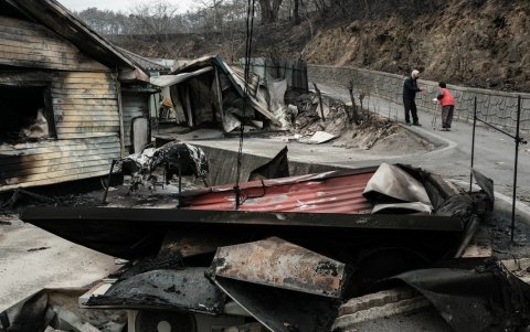Una productora de manzanas de 81 años que perdió su cosecha (derecha) habla con sus vecinos frente a su casa, quemada por un incendio forestal hace dos días, en Andong, el 27 de marzo de 2025.