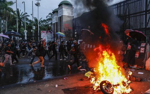 Los manifestantes queman una motocicleta durante una manifestación contra la recién aprobada ley militar del país frente al edificio del parlamento