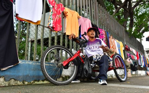 Ronny Chávez vende ropa en los exteriores del hospital Teodoro Maldonado Carbo. Él traslada la mercadería en el triciclo que impulsa con las manos, ante la discapacidad en las piernas.